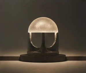 An illuminated sculptural dome resting on a dark stone base.