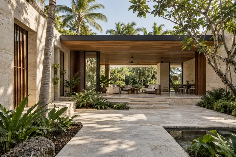 A planted courtyard framed by pale architecture and tropical foliage.